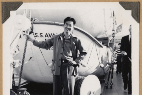 Gary Kikawa poses next to a lifeboat (ddr-densho-542-350)