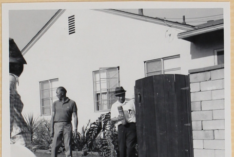 Man standing next to gate in driveway (ddr-densho-522-100)