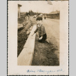 Jon David Sakura kneeling by side of road (ddr-densho-523-84)