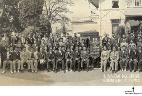 Panorama of large group of people posing outside building with banner: Y.M.B.A. Leave of North America (ddr-ajah-3-181)