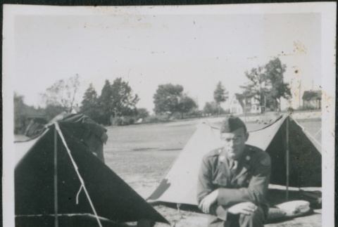 Man kneeling next to tent with gear (ddr-densho-434-465)