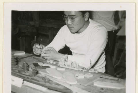 Man working on a model ship (ddr-densho-37-1243)