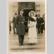 Woman wearing fur with man in uniform outside building (ddr-densho-426-2037)