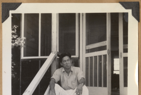 Gary Kikawa smoking on porch steps (ddr-densho-542-140)