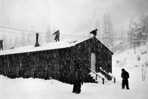 Men shoveling snow from roof of barracks (ddr-ajah-2-782)