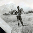Shiro Aoki in army fatigues with mountain in background (ddr-densho-474-243)