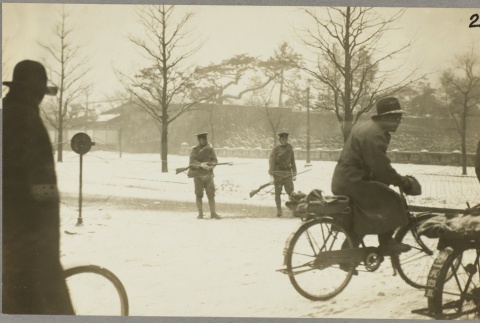 Civilians riding bicycles past two sentries with rifles (ddr-njpa-13-1225)