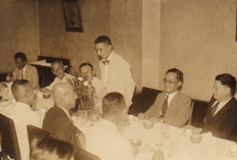 A man standing speaking to others seated at a table (ddr-njpa-4-127)