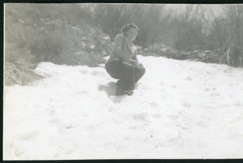 Photograph of a women crouching in the snow on a hillside (ddr-csujad-47-307)