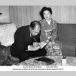 Man signing book seated next to woman (ddr-ajah-3-33)
