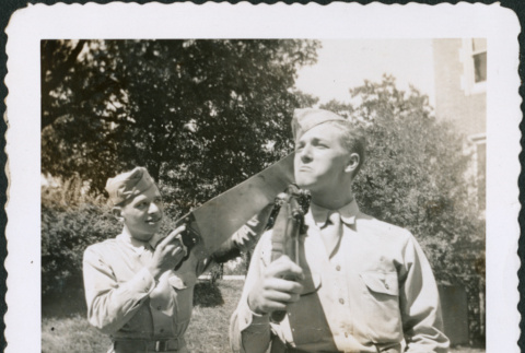 Man pretending to saw gun held by another man (ddr-densho-434-459)