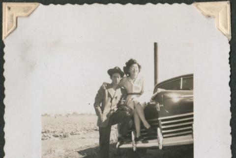 Young man leansing against a woman seated on car (ddr-densho-321-181)