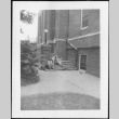 Two men and a woman sitting on stairs outside building (ddr-densho-434-497)