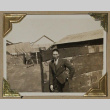 Man in a suit leans against a fence (ddr-densho-404-222)