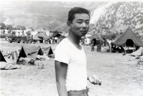 Hisashi Nakashima standing with army camp in background (ddr-densho-474-231)
