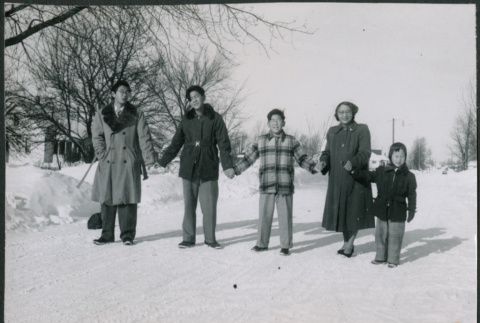Sakura family standing in snow holding hands (ddr-densho-523-234)