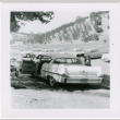 Car in parking lot, Tomoye (Nozawa) Takahashi standing on one side (ddr-densho-426-2203)