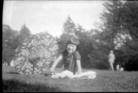 Young girl with parasol sitting in grass (ddr-densho-426-1819)