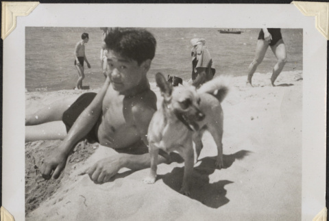 Man laying on beach with small dog (ddr-densho-466-862)