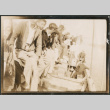 Group of men sitting on dock next to boat (ddr-densho-483-567)