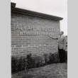 Alvah A. Scott Elementary principal pointing to the school's name plate (ddr-njpa-2-356)