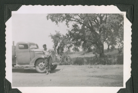 Shirtless man leaning against truck (ddr-densho-471-175)