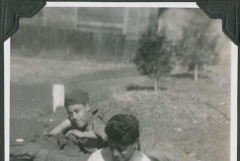 Two men relaxing in yard with barrack in background (ddr-ajah-2-341)