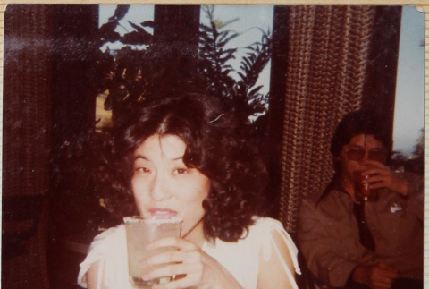 Woman with drink, man sitting in background (ddr-densho-426-1316)