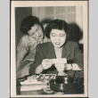 Two women looking at photos (ddr-densho-293-160)