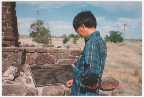 Photo of Kenji Ima reading the Minidoka visitor plaque (ddr-densho-483-11)