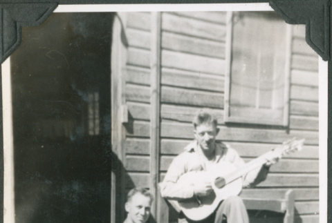 Two men on steps of barracks, one with guitar, the other with a washboard (ddr-ajah-2-363)