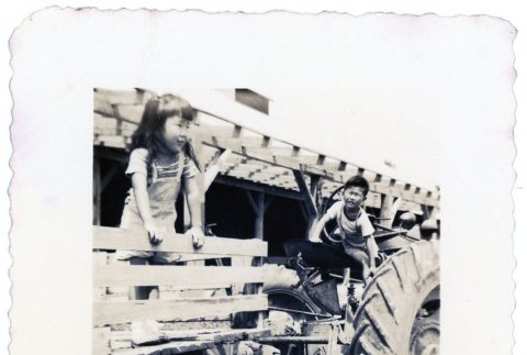 Children playing on a tractor (ddr-densho-373-67)
