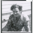 Photograph of Lucy Adams sitting on the grass in front of staff housing at Manzanar (ddr-csujad-47-170)