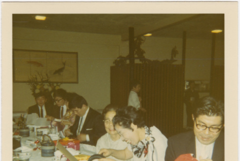 Group seated at a table opening gifts (ddr-densho-426-169)