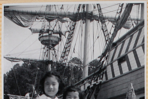 Two girls standing on dock by masted ship (ddr-densho-522-28)