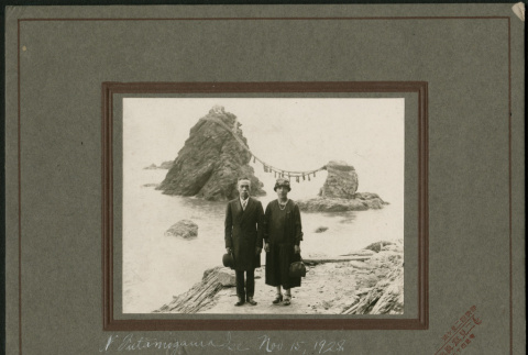 A couple poses on the beach with a shrine in the background. (ddr-densho-359-1085)