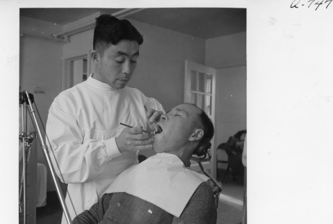Dentist, Dr. T. Nakamura, working on a patient's teeth (ddr-fom-1-856)