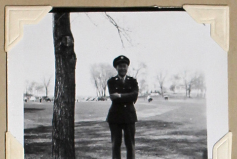 Man in military uniform stands with arms folded (ddr-densho-404-389)