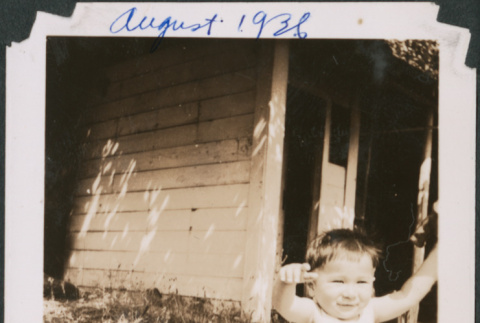 Baby sitting on blanket outside house (ddr-densho-483-571)
