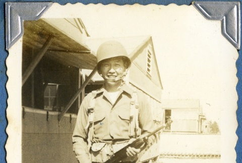 Soldier holding a rifle outside barracks (ddr-densho-22-326)