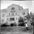 Woman watering lawn of house on 36th and Shoreview (ddr-densho-426-910)