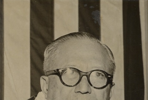 Man wearing leis in front of a flag (ddr-njpa-2-394)