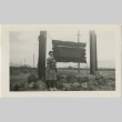 Woman standing in front of camp entrance sign (ddr-manz-7-2)