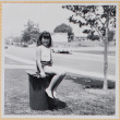 Girl sitting on trash can in yard (ddr-densho-522-103)