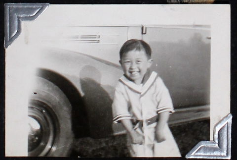 Young boy grins in front of a car (ddr-densho-404-33)