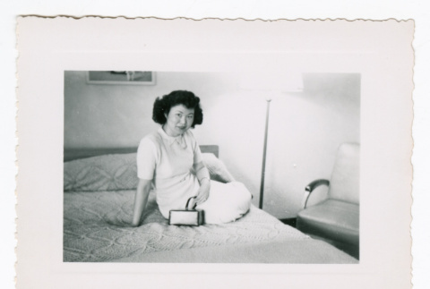 Lillie (Yamato) Komai sitting on hotel bed (ddr-densho-562-64)