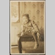 Nisei child sitting on a table with a statue (ddr-densho-259-155)