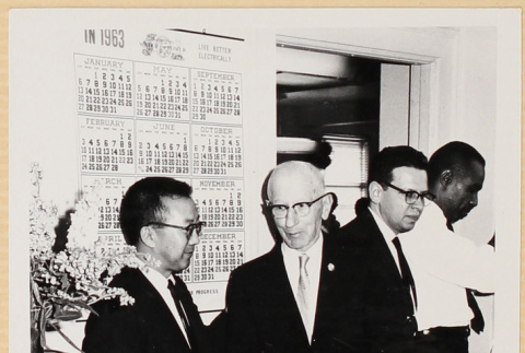 Two men standing by large wall calendar (ddr-densho-522-86)