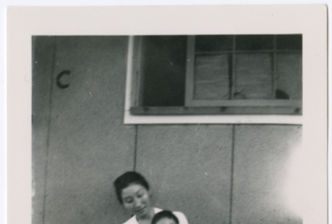 Woman holding baby outside barracks (ddr-densho-329-961)