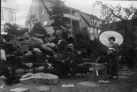Girl in a kimono in front of the Kubota Gardening Company sign. (ddr-densho-354-110)